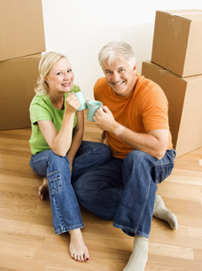 Image of a couple drinking coffee between moving boxes - International Moving Expenses and Reimbursements